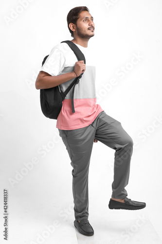 Handsome Indian college student carrying bag on white background.