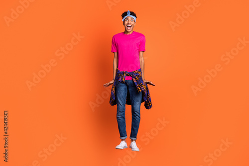 Full length body size photo of young hipster jumping up careless crazy staring isolated bright orange color background