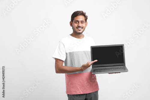 Indian college student showing laptop screen on white background.