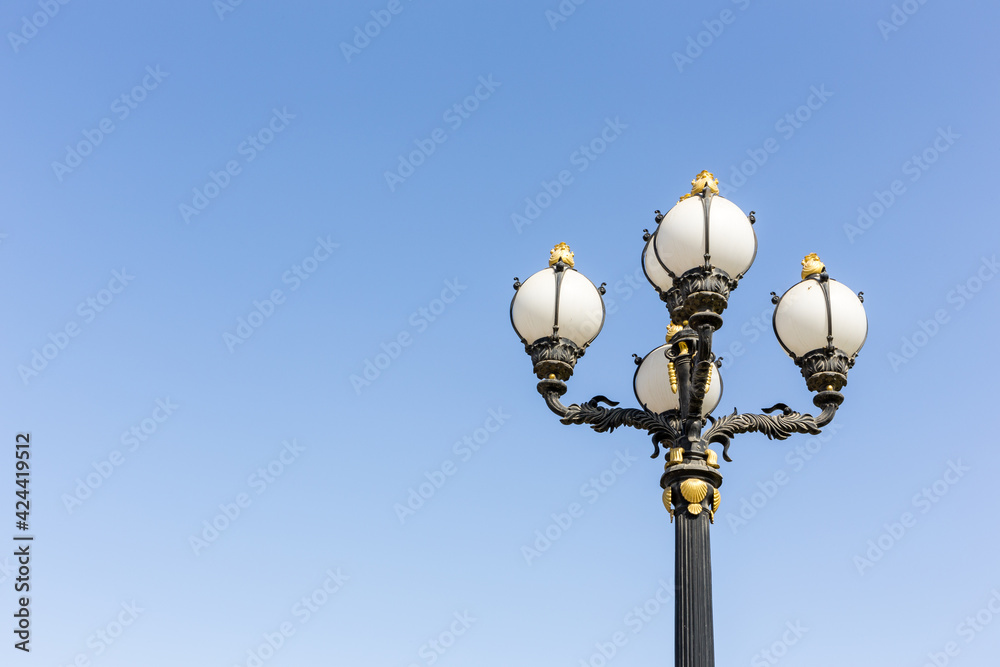 Vingate style street lamp with golden ornaments and round bulbs against clear blue sky, Dubai, United Arab Emirates. Vingate style street lamp with golden ornaments and round bulbs against clear blue sky, Dubai, United Arab Emirates.