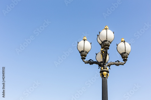 Vingate style street lamp with golden ornaments and round bulbs against clear blue sky, Dubai, United Arab Emirates.