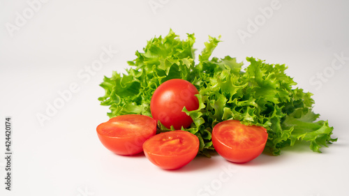 Fresh lettuces salad with fresh tomatoes isolated on white background. Ripe tomatoes scattered on the table