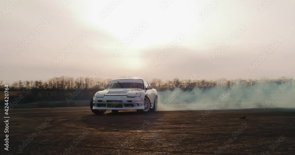 White car drifting against cloudy sunset sky White car drifting against cloudy sunset sky