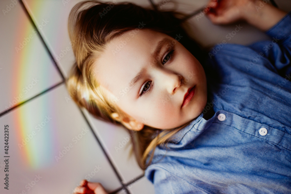 Rainbow reflection on the face of a little girl lying on the floor Rainbow reflection on the face of a little girl lying on the floor