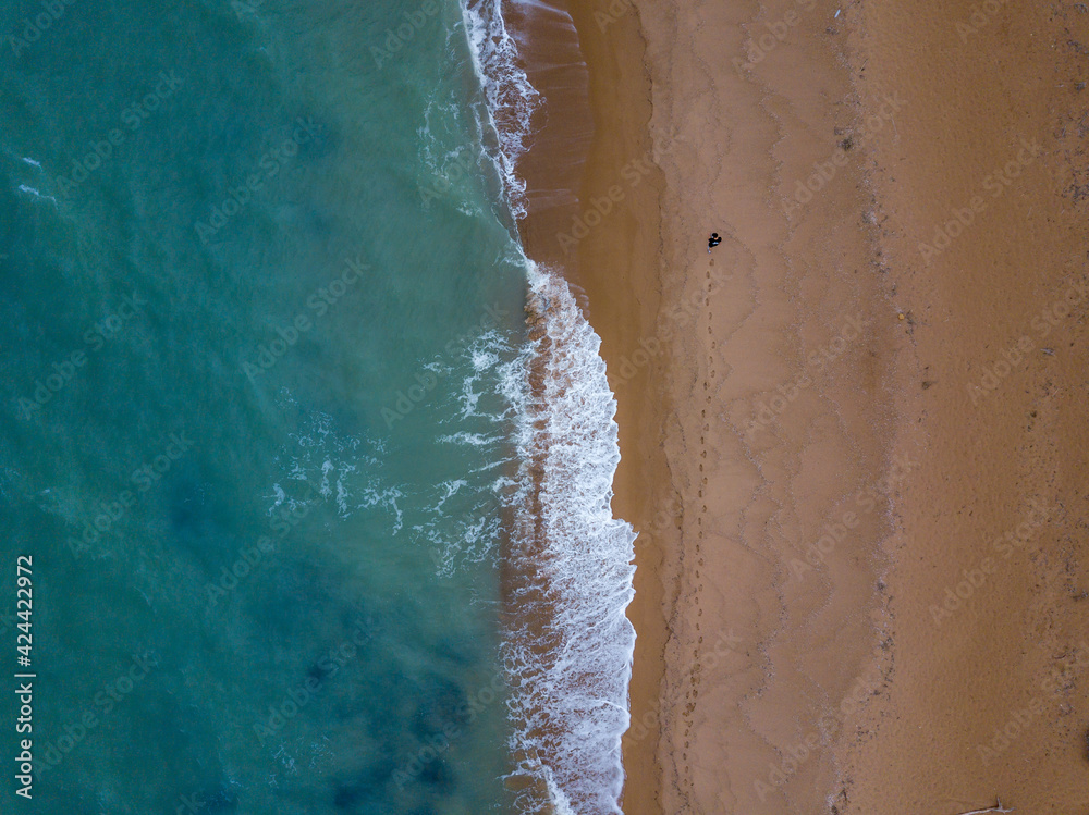 Aerial beach view from above with a walking person in the frame