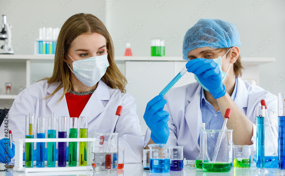 Caucasian man and woman scientist are discussing about testing results. Man hold test tube and science equipment microscope, many test tube put on table in laboratory Caucasian man and woman scientist are discussing about testing results. Man hold test tube and science equipment microscope, many test tube put on table in laboratory