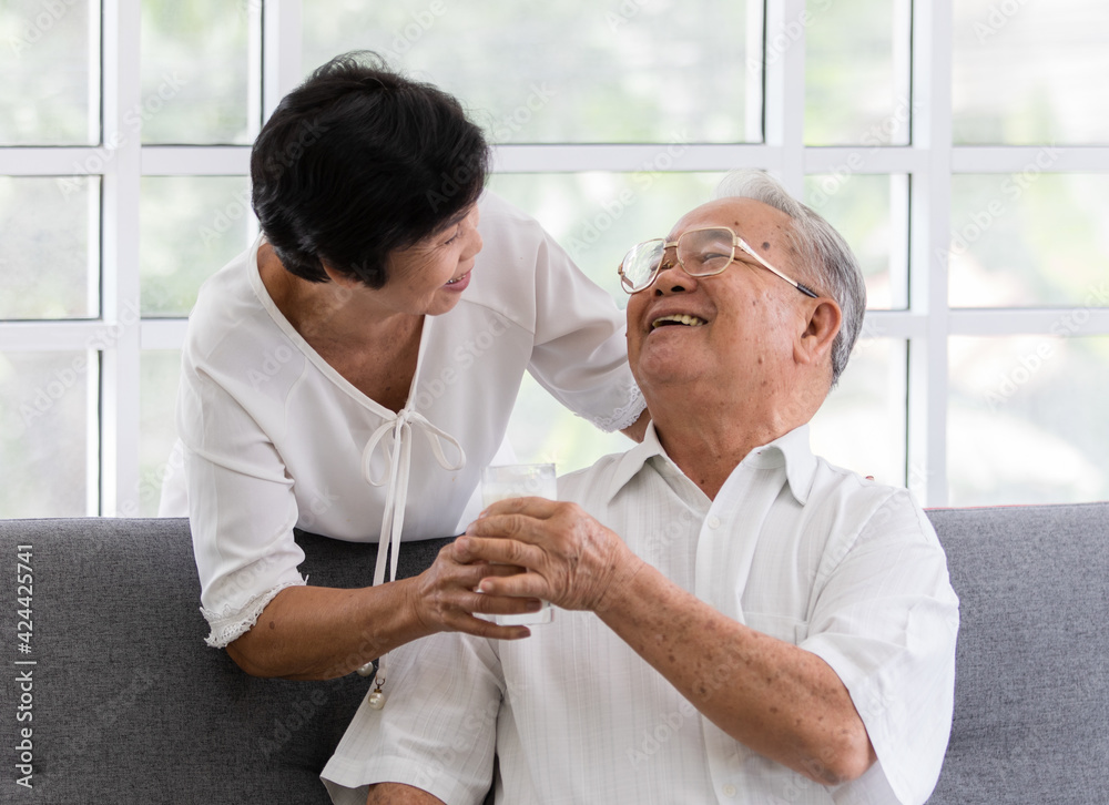 Obraz premium Senior old Asian man and woman lovers holding a glass of milk and drinking together. Idea for the healthcare of elder people