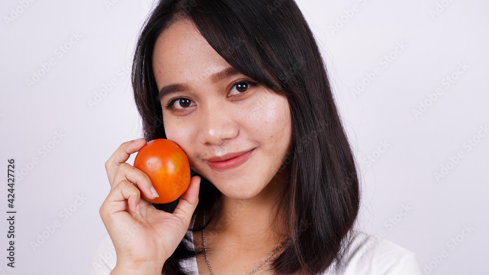 Close up beautiful asian women with a tomato isolated on white background Close up beautiful asian women with a tomato isolated on white background