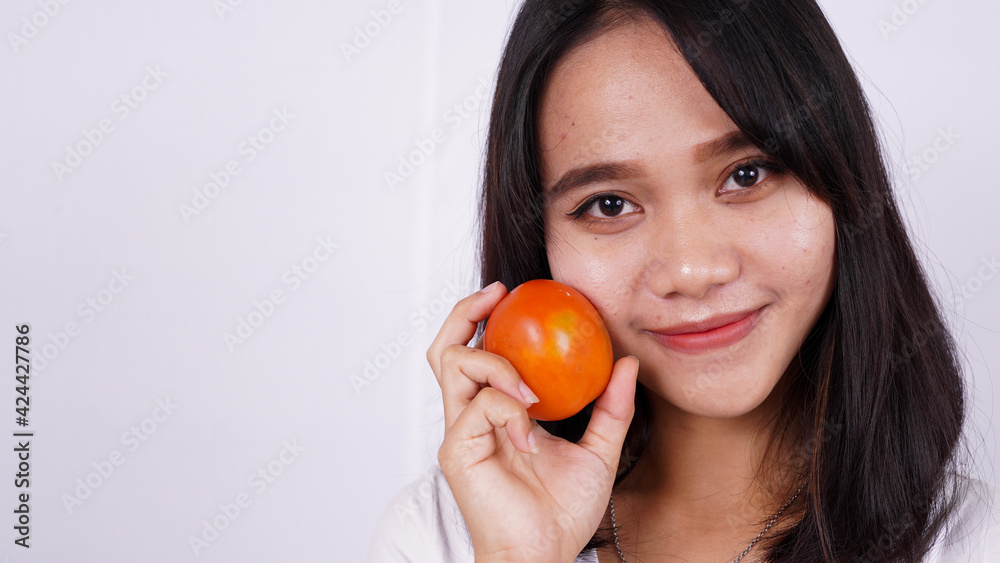 Close up beautiful asian women with a tomato isolated on white background Close up beautiful asian women with a tomato isolated on white background