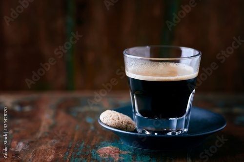 Coffee in glass cup on rustic wooden background. Close up.