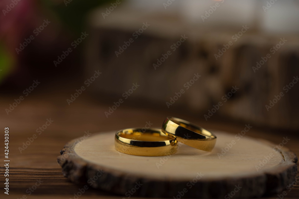 Two golden wedding rings close up on natural wooden background. Eco wedding invitation card concept. Two golden wedding rings close up on natural wooden background. Eco wedding invitation card concept.