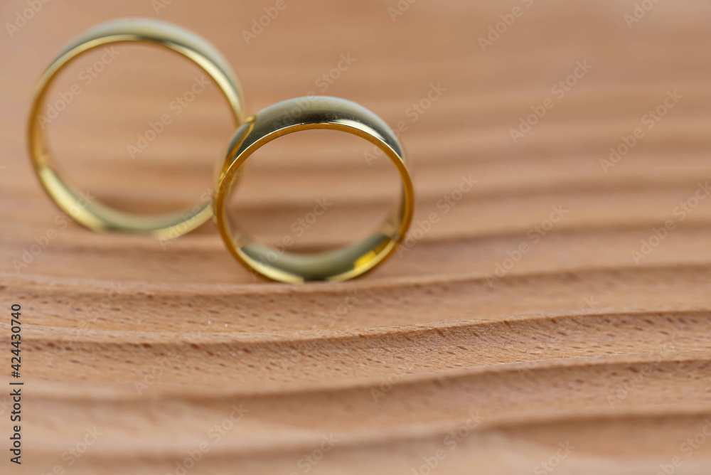 Two golden wedding rings close up on natural wooden background. Eco wedding invitation card concept. Two golden wedding rings close up on natural wooden background. Eco wedding invitation card concept.