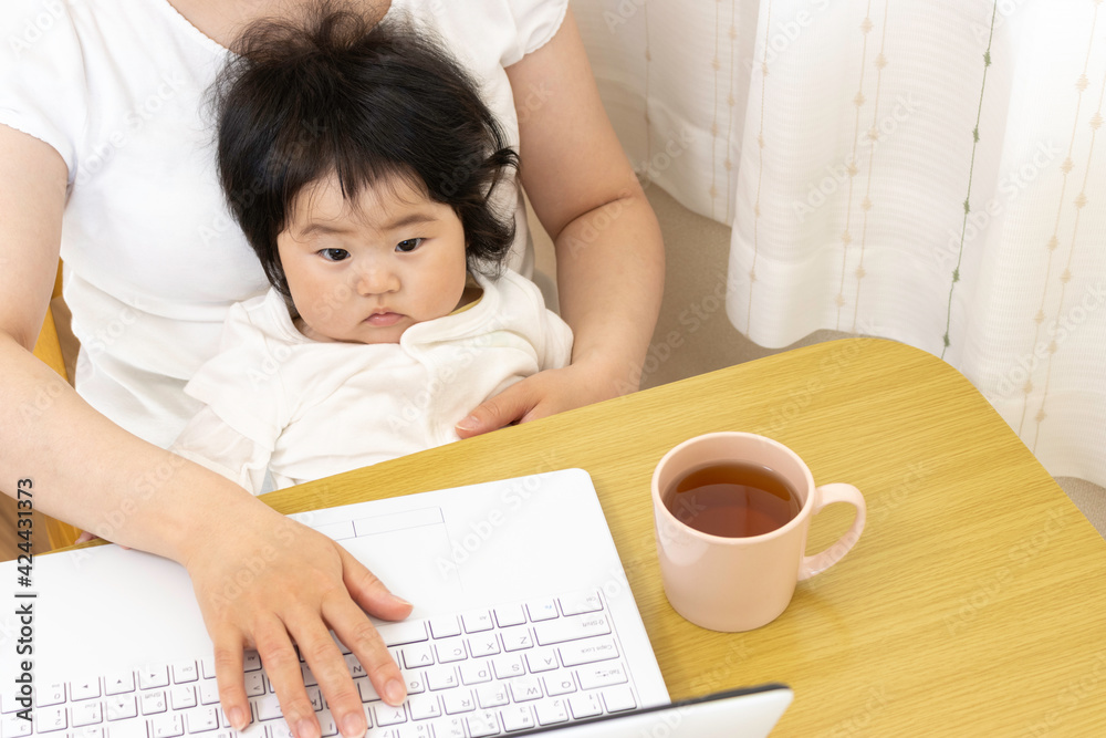 赤ちゃんを膝に座らせて、ノートパソコンを使う女性。赤ちゃん(0歳、生後8か月、日本人、女の子) 赤ちゃんを膝に座らせて、ノートパソコンを使う女性。赤ちゃん(0歳、生後8か月、日本人、女の子)