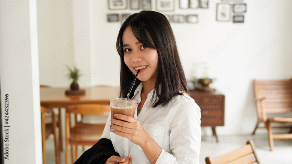 Beautiful young asian businesswoman in suit standing holding brown coffee cup in caffe while having a coffee break. Beautiful young asian businesswoman in suit standing holding brown coffee cup in caffe while having a coffee break.