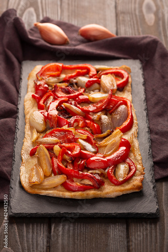 Spanish coca with onion and bell pepper on a dark wooden background