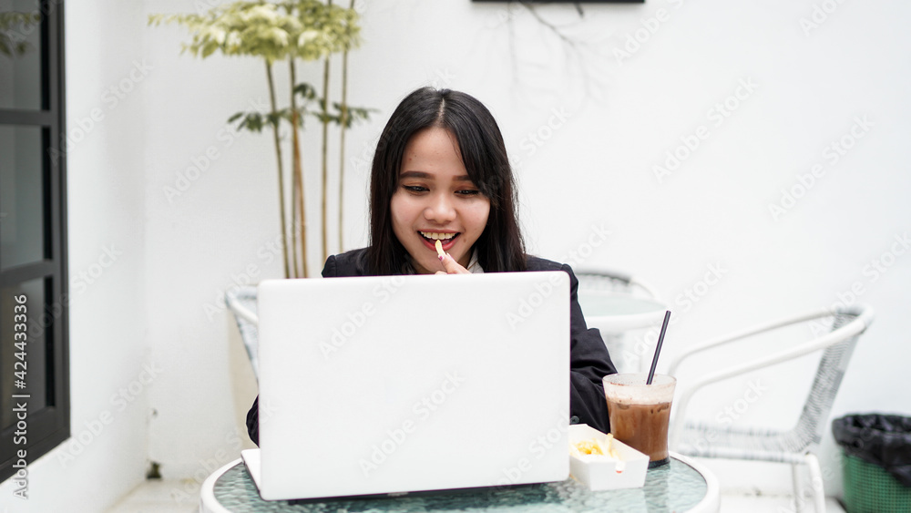 Asian business woman eating and working with his laptop at cafe Asian business woman eating and working with his laptop at cafe