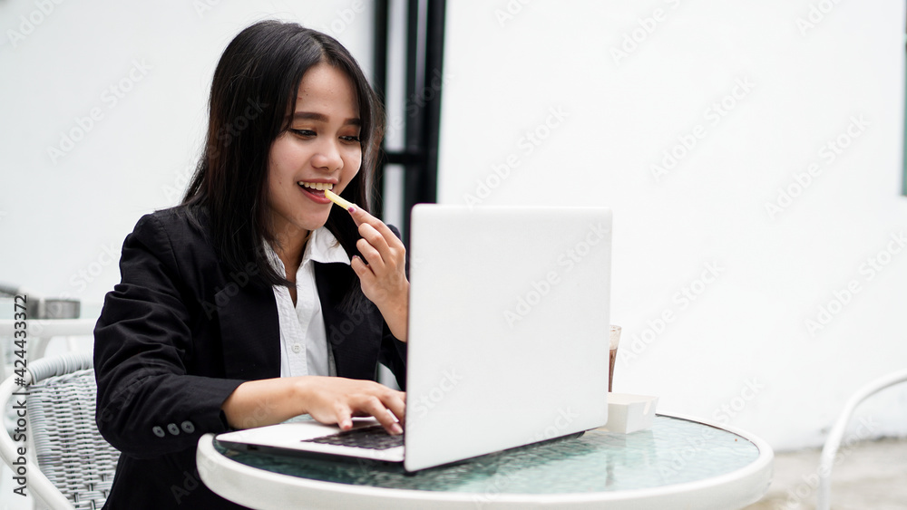 Asian business woman eating and working with his laptop at cafe Asian business woman eating and working with his laptop at cafe