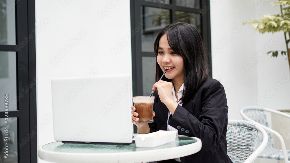 Asian business woman dringking and working with his laptop at cafe Asian business woman dringking and working with his laptop at cafe