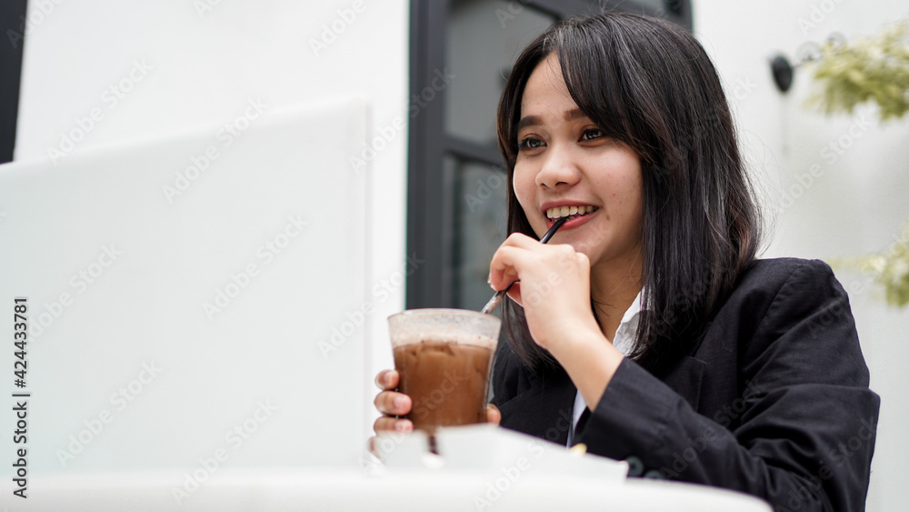 Asian business woman dringking and working with his laptop at cafe