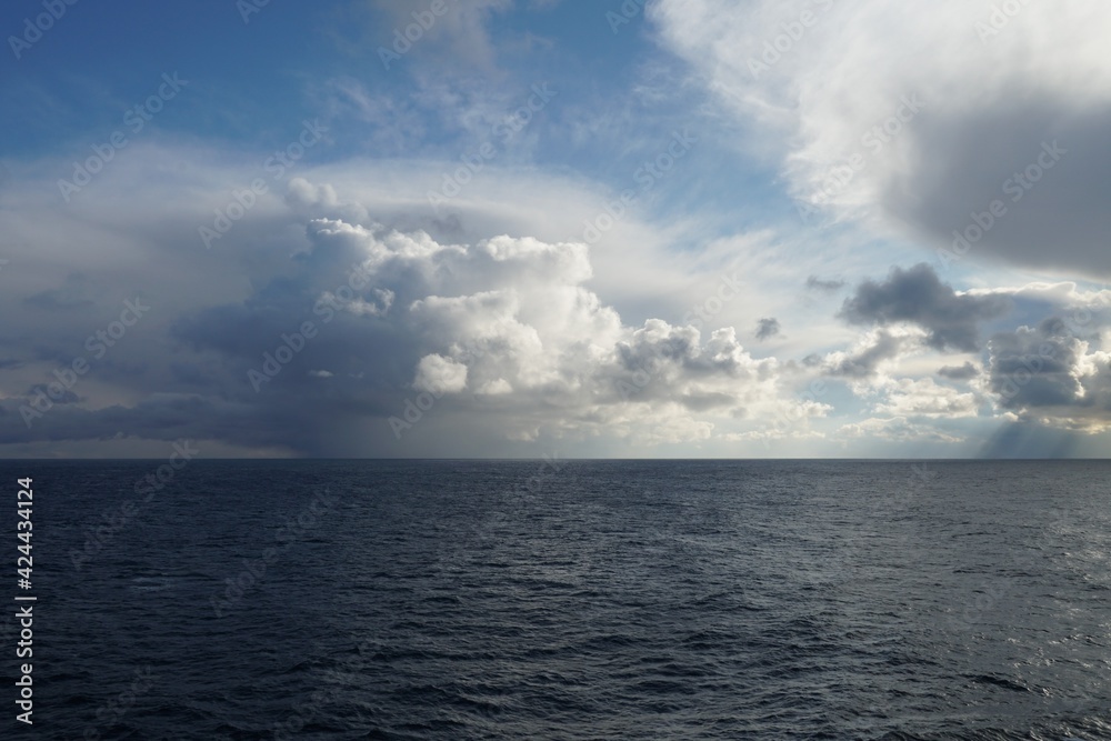 Largely overcast sky with heavy rainfall clouds bringing abundant rainfall and atmospheric precipitation observed on Pacific ocean near North America coast.