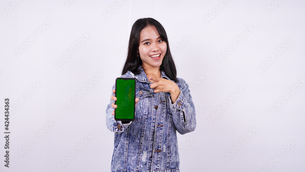 Asian women smiling wearing jeans jacket and holding green screen phone with isolated white background Asian women smiling wearing jeans jacket and holding green screen phone with isolated white background