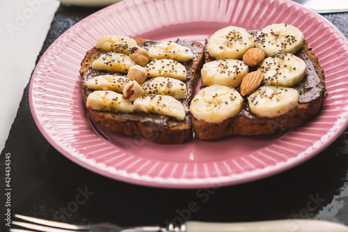 Toasted whole wheat bread with chocolate nuts paste nutella topping, banana, chia seeds, almonds and hazelnuts toast. Healthy proper nutrition for breakfast