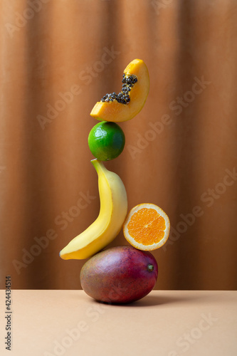 Fototapeta Naklejka Na Ścianę i Meble -  Conceptual creative still life with balancing fruits over fabric background, vertical