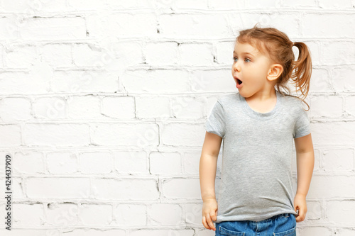 Excited funny child with expression face in casual clothes over background and looking at copy space. Concept of advertising and promoting goods,seasonal sale,discount, shopping, information and news