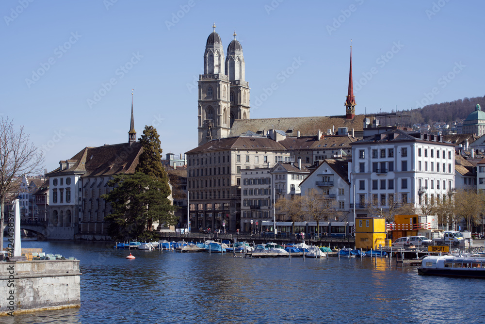 Old town of Zurich with church Grossmünster (great minster) and river Limmat in the foreground. Photo taken April 1st, 2021.