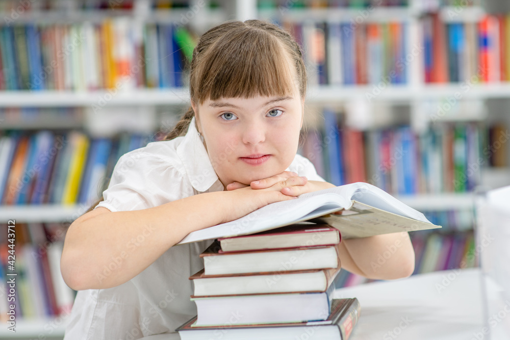 Portrait of a pensive girl with syndrome down at library.  Education for disabled children concept