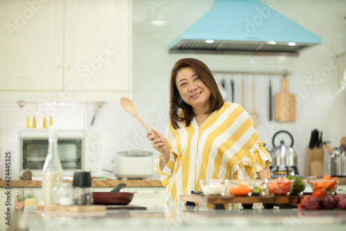 Woman cooking rice with vegetables in kitchen