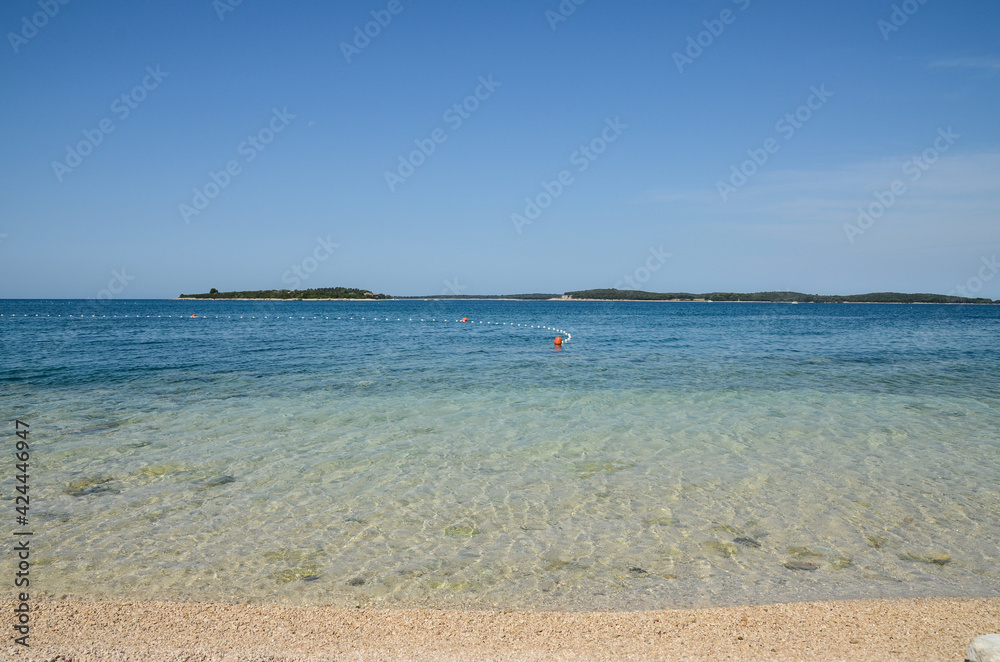 Fototapeta premium Exotic beach with sand. Soft sea waves on beautiful beach with pebbles. Vacation, travel and tourism concept.