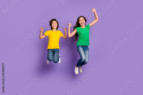 Full body photo of little brunette children jump celebrate win wear casual clothes isolated on violet color background