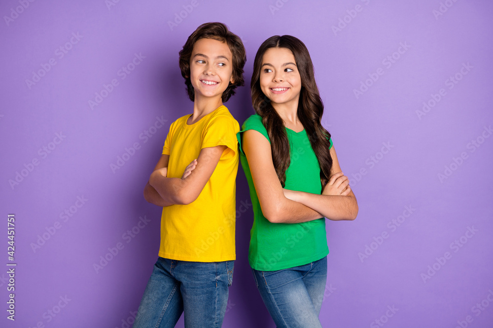 Photo of happy brown haired children stand back to back folded arms smile isolated on purple color background Photo of happy brown haired children stand back to back folded arms smile isolated on purple color background