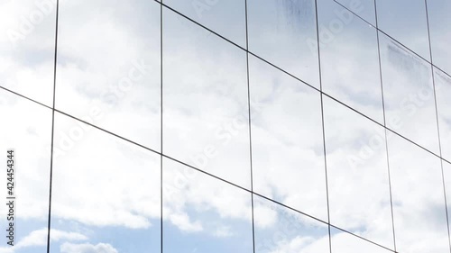 Skyscraper office building glass square windows blue cloudy sky reflection modern abstract corportate background texture, gentle movement, closeup, long clip. Sky reflecting in the windows, angle