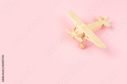 wooden model of a passenger plane with on a pink background. tourism and travel concept.