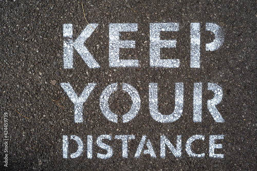 Keep Your Distance is written on the road amid COVID-19 pandemic to remind people to keep social distance