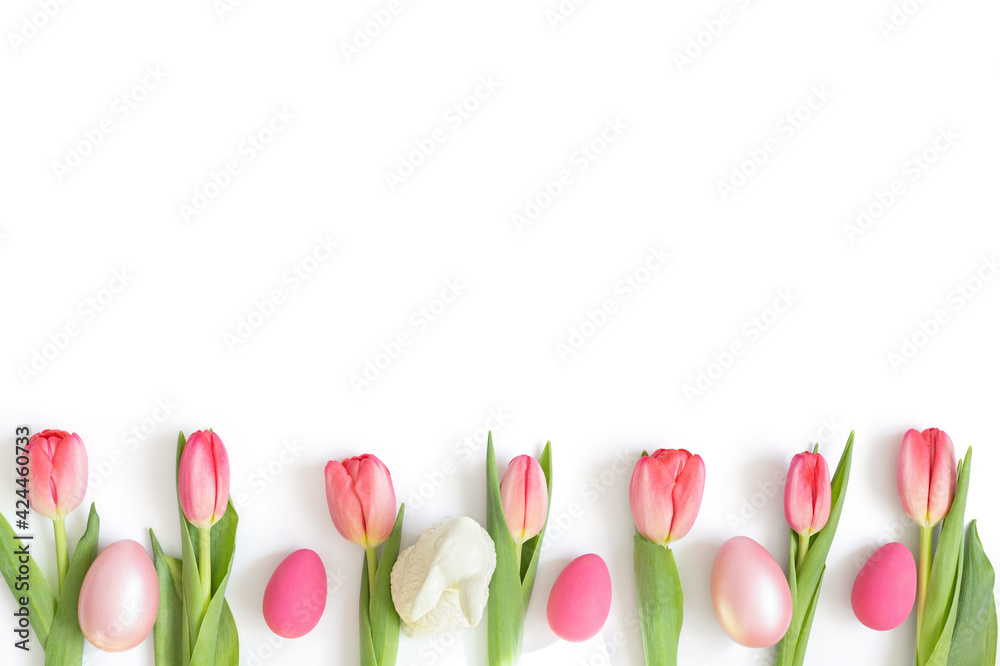 Easter composition with pink tulips, eggs and an Easter bunny isolated on a white background. Copy space, top view, flat lay.