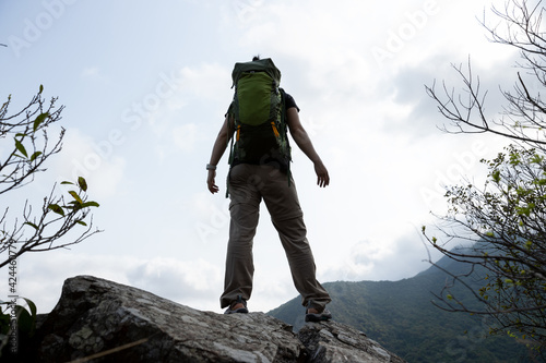 Photography Woman hiker standing on mountain top cliff edge