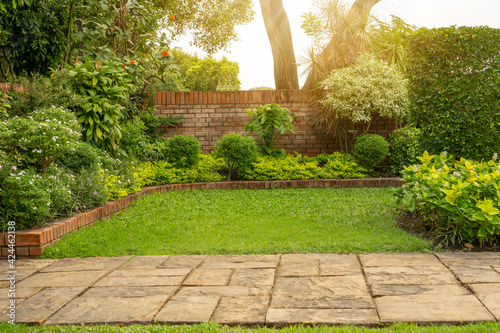 Slika na platnu Back - front yard English cottage garden, green grass lawn, colorful flowering p
