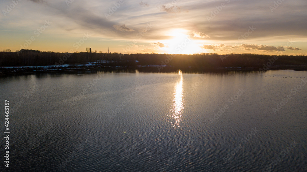 Aerial view of a beautiful and dramatic sunset over a forest lake reflected in the water, landscape drone shot. Blakheide, Beerse, Belgium. High quality photo