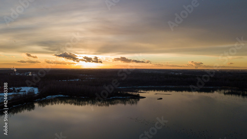 Aerial view of a beautiful and dramatic sunset over a forest lake reflected in the water, landscape drone shot. Blakheide, Beerse, Belgium. High quality photo