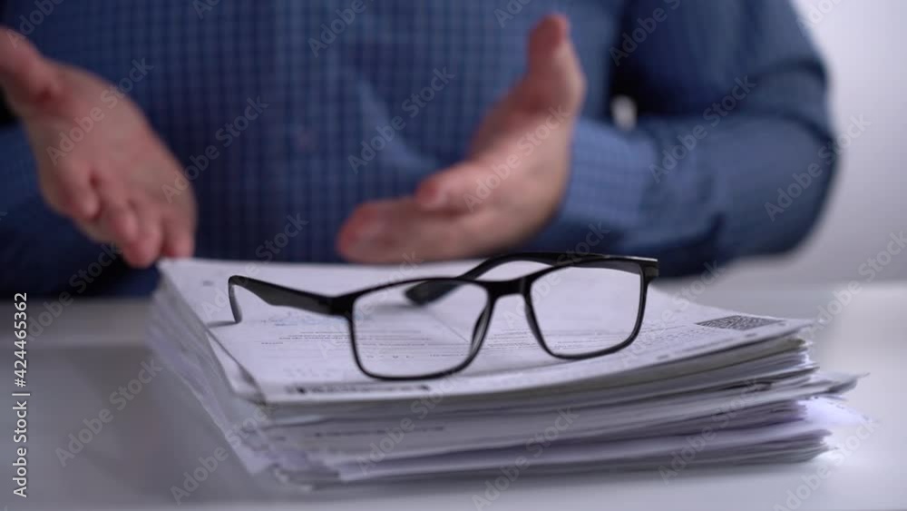 Stack of Papers and Glasses on the Background of the Manager. Manager Explains and Leads with Hands. Close-up. Stack of Papers and Glasses on the Background of the Manager. Manager Explains and Leads with Hands. Close-up.