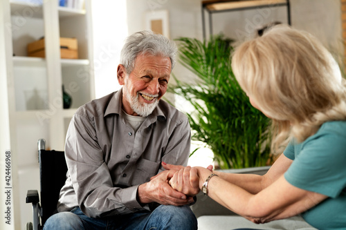  Elderly man in wheelchair. Happy husband and wife talking.