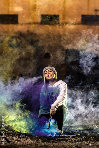 fashion young woman wearing street clothes with colorful smoke looking happy and confidant