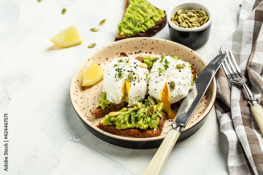 Healthy sandwich with avocado and poached eggs. Delicious breakfast or snack on a light background, top view