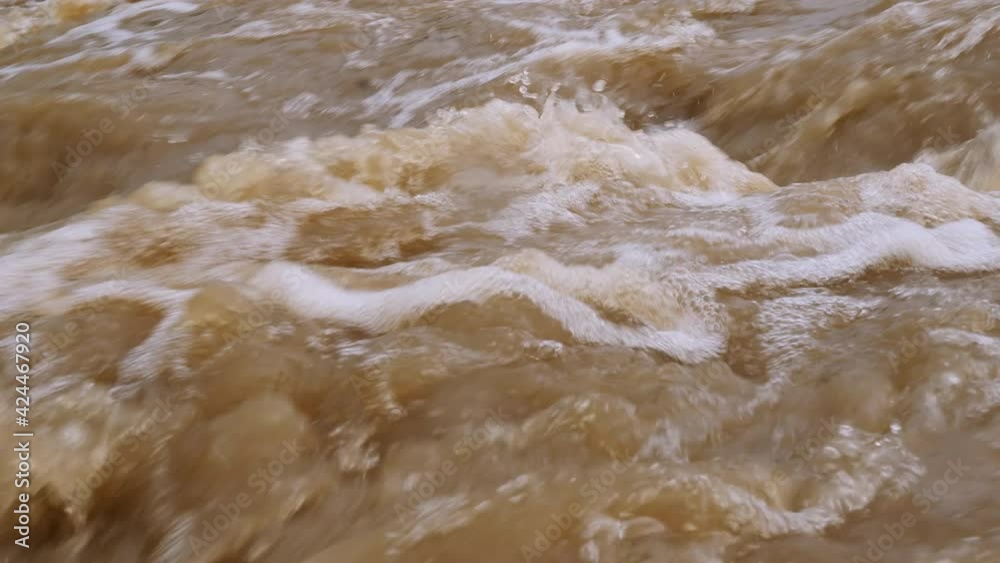 Raging river with dirty water. Crowded river overflows its banks. Natural disasters, extreme weather. Disaster flood deluge and water flow in close up. Raging river with dirty water. Crowded river overflows its banks. Natural disasters, extreme weather. Disaster flood deluge and water flow in close up.