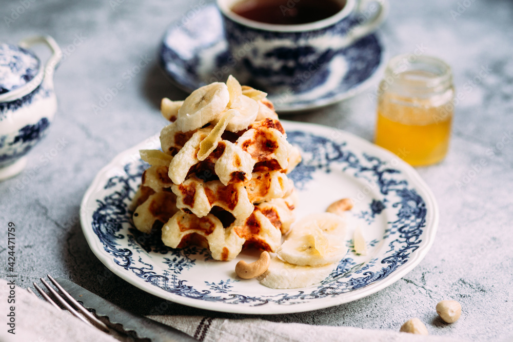 Belgian waffles with banana and honey on a vintage blue plate Belgian waffles with banana and honey on a vintage blue plate