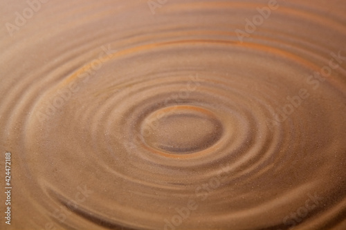 Circles on the surface of the water, through which the sand is visible. Background image