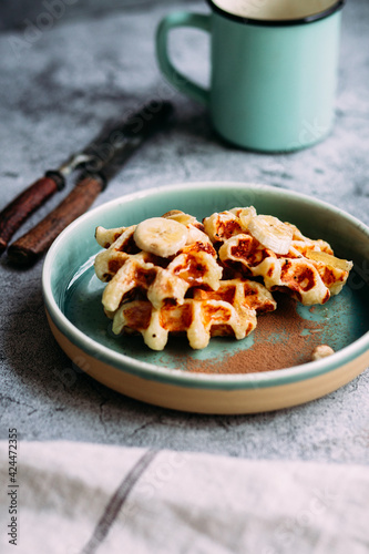 Belgian waffles with banana and honey on a turquoise plate